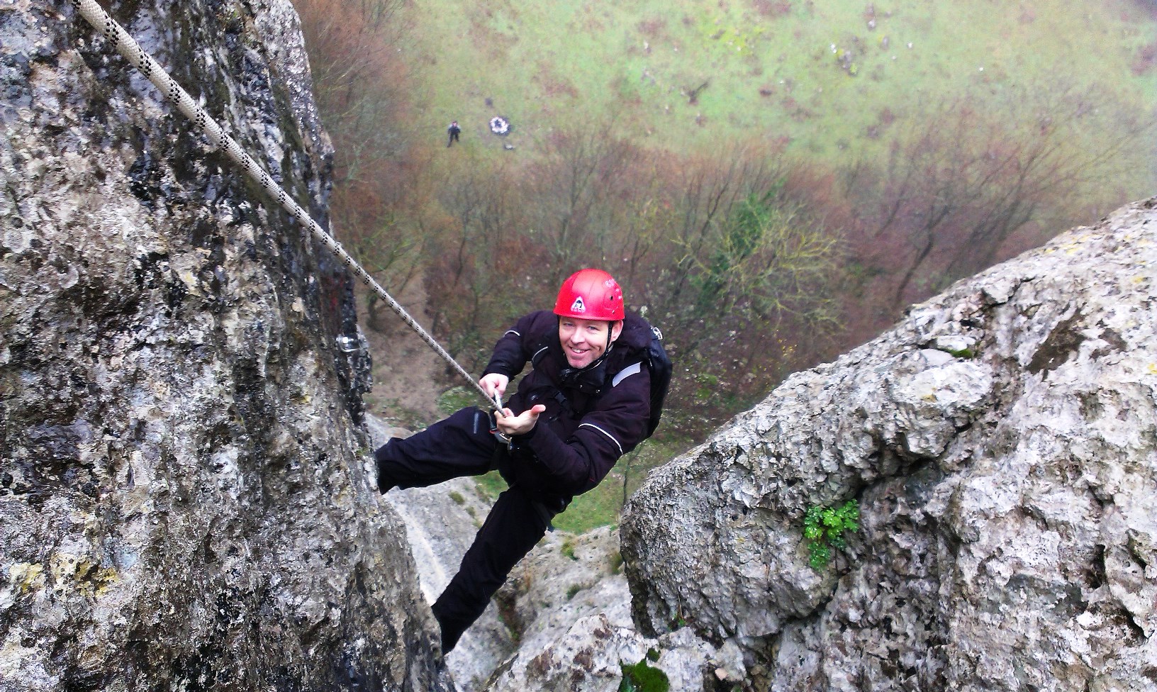 Mads Cronquist abseiling down a cliff wearing a red helmet