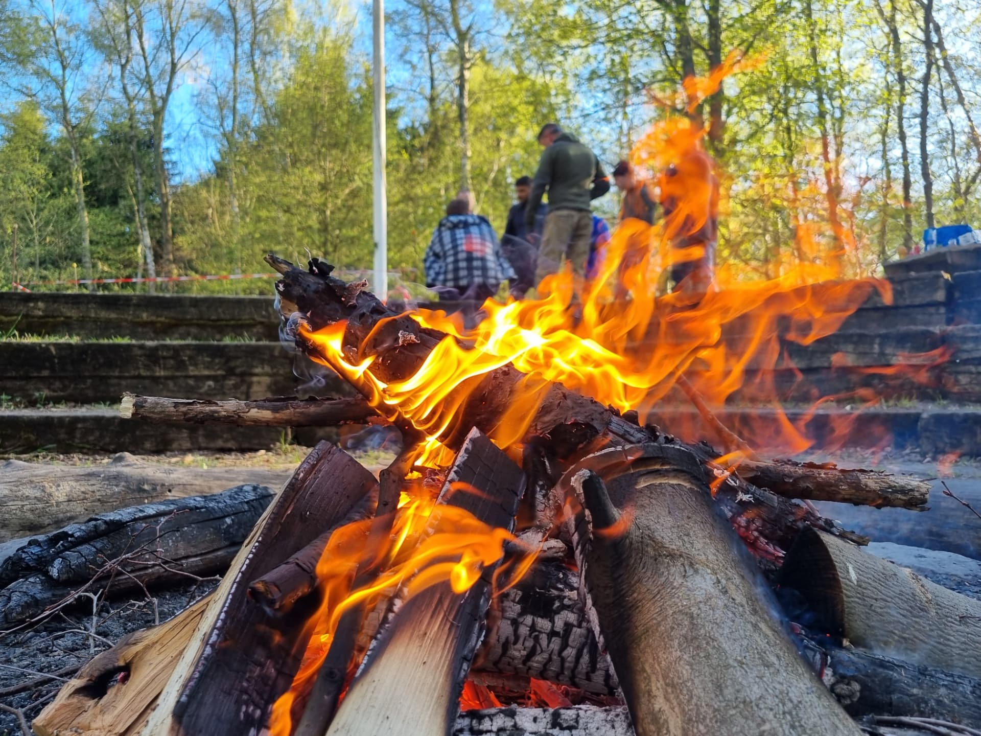 Campfire in the forest with participants in the background