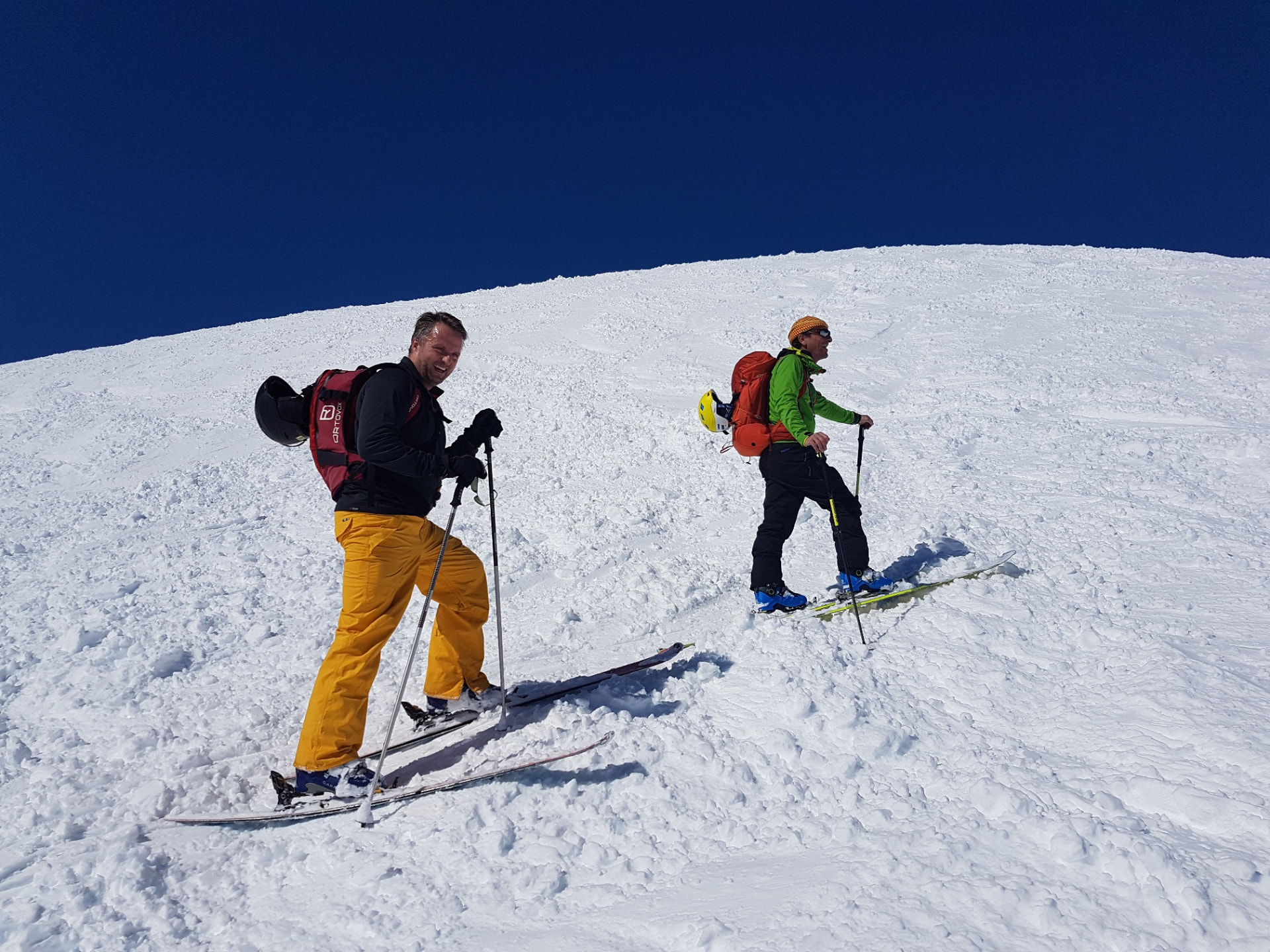 To voksne på randonnée-ski på vej op ad en snedækket bjergside