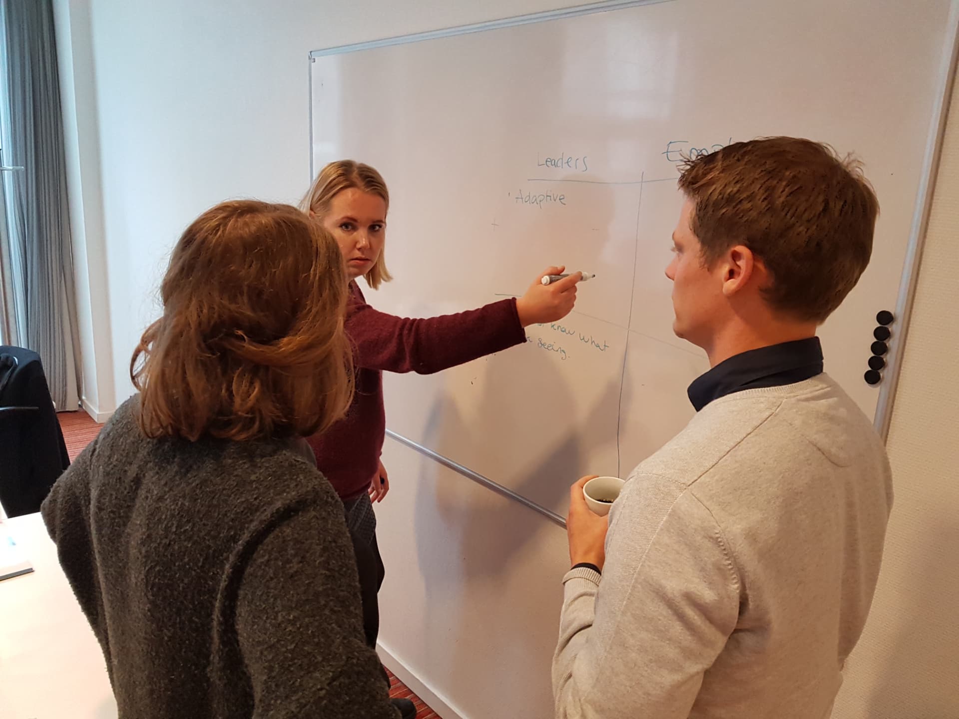 Participants working at a whiteboard during the leadership development programme at Ageras.